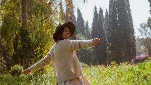 A carefree woman in a sunlit garden, enjoying nature and freedom.