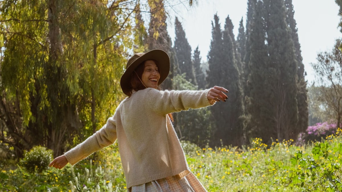 A carefree woman in a sunlit garden, enjoying nature and freedom.